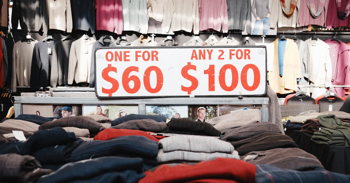 Espositore di maglioni con cartello promozionale “due per cento dollari”, esempio di pricing tradizionale a sentimento